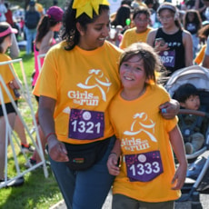 A Girls on the Run participant and Running Buddy celebrate with a side hug as they finish the run.