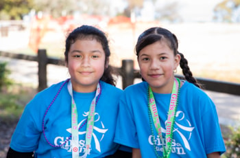 Girls on the Run Coach and participant both smile while holding hands at 5K 